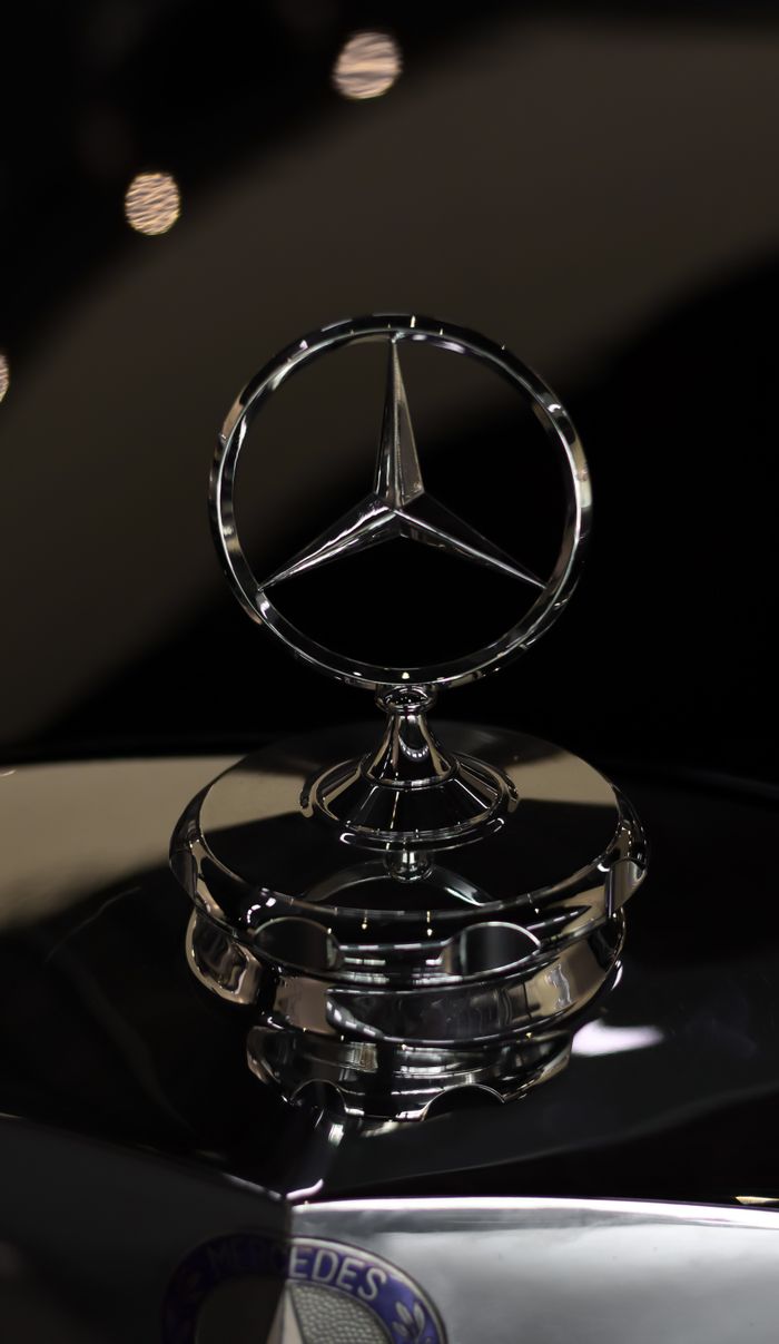 Elegant car hood ornament in a glistening chrome finish with soft lighting, capturing luxury and detail.