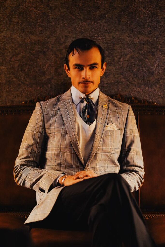 Stylishly dressed man sitting on a leather couch in Ankara, Türkiye.
